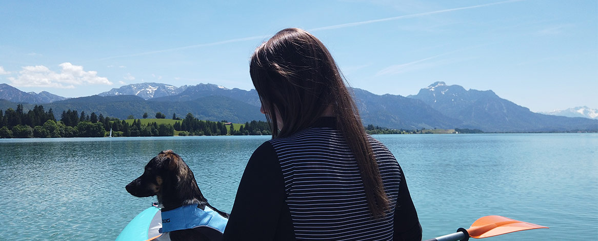 Kanufahren auf Forggensee mit Hund und Bergkulisse im Hintergrund