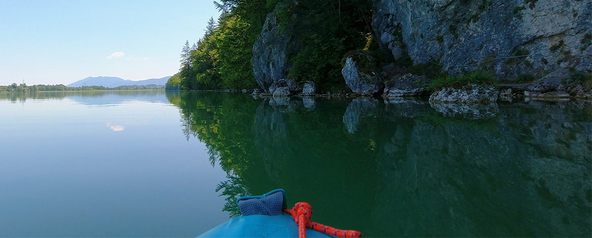 Blick auf Wanderweg an Felswand vom Kajak aus bei Paddeltour am Weißensee im Ostallgäu